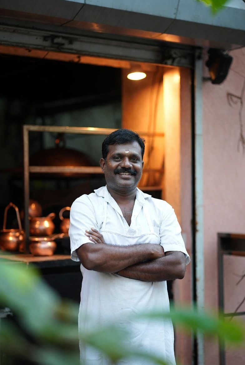 An independent Indian restaurant owner standing proudly at the entrance of his restaurant